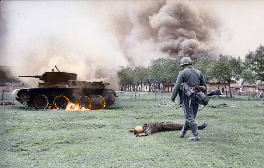 A Dead Soldier Lies In Front Of A Burning Tank