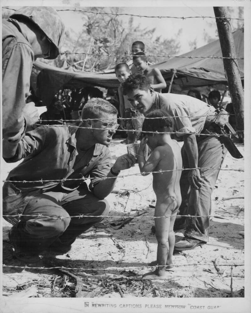 Soldiers Console Naked Child Behind Wire