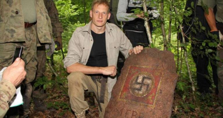 Man Holding Swastika Emblazoned Boulder