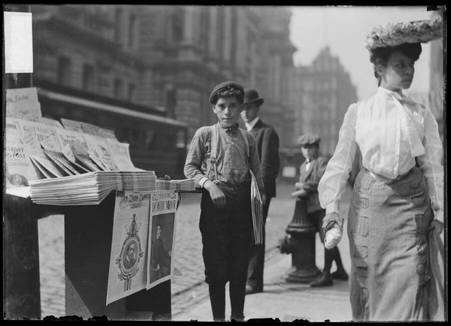 Newsboy Next To Paper Stand